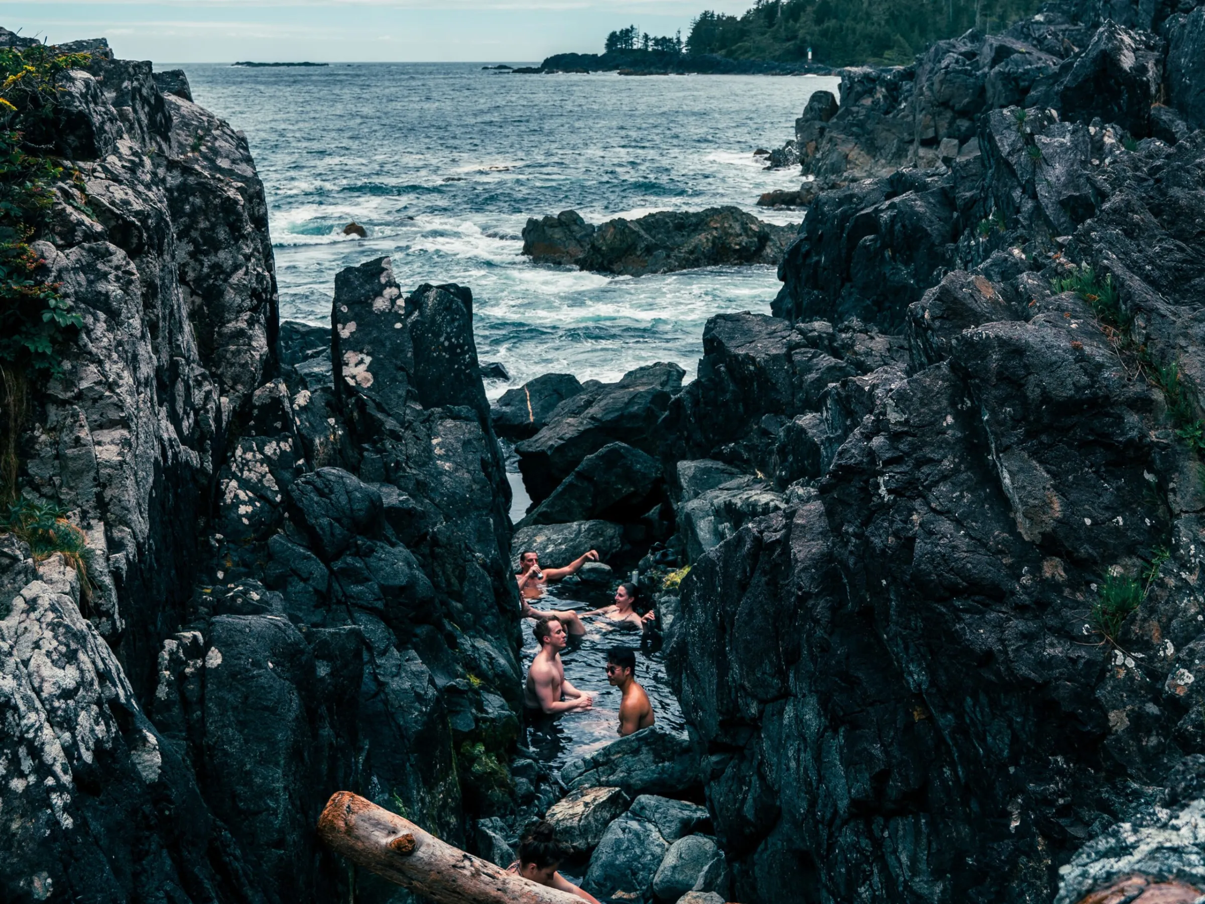 group of people in the natural rock thermal pools at hot springs cove