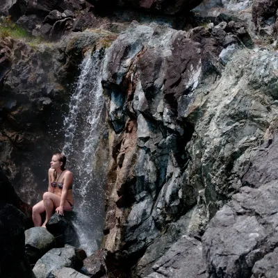 lady sits under waterfall at hot springs cove
