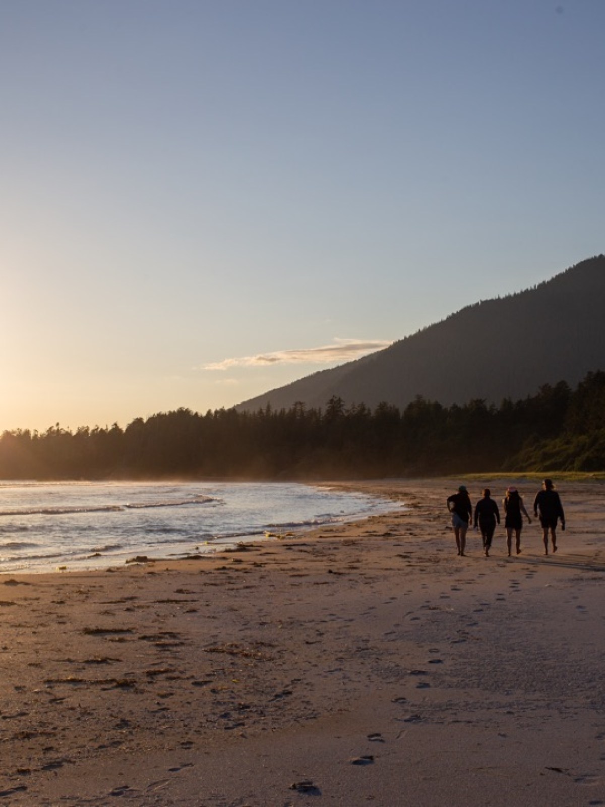 a couple of people standing on top of a sandy beach