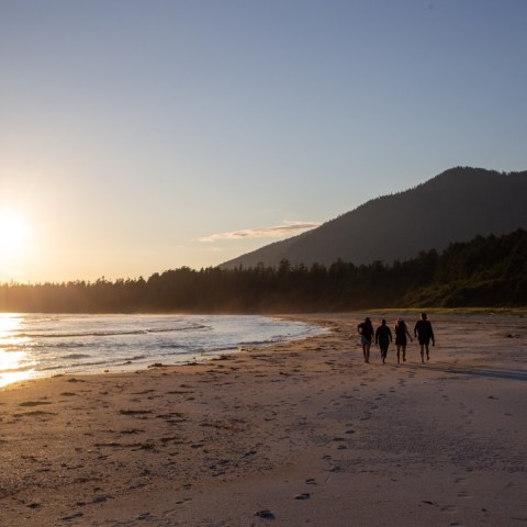a couple of people standing on top of a sandy beach
