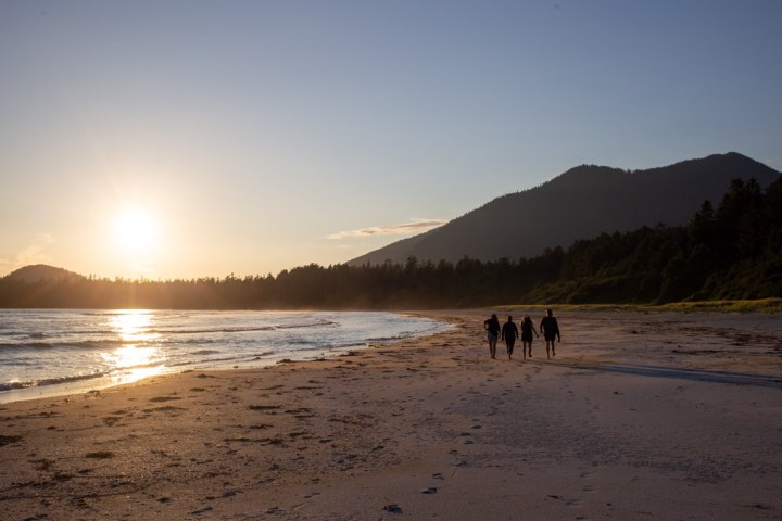 a couple of people standing on top of a sandy beach
